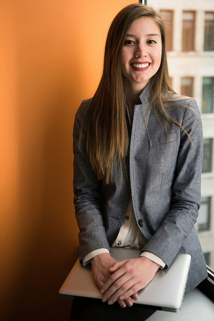 Junge Frau im Business-Outfit mit Laptop auf dem Schoß – steht sinnbildlich für BWL Berufe wie den Account Manager.