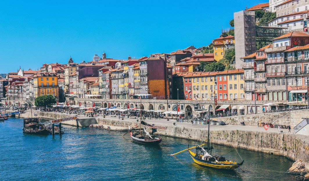 Bunte Häuserfassaden und Boote am Fluss in Porto, Symbol für günstiges Reisen als Student in Portugal mit Kultur.