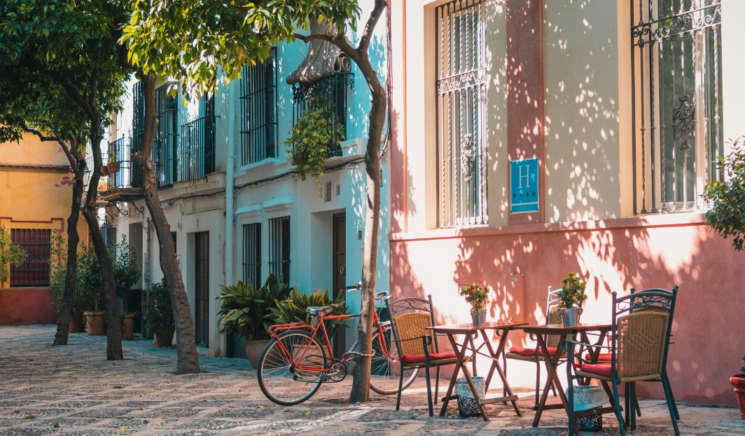 Bunte Altstadt mit Café und Fahrrad, Beispiel für günstiges Reisen als Student in Spanien mit mediterranem Flair.