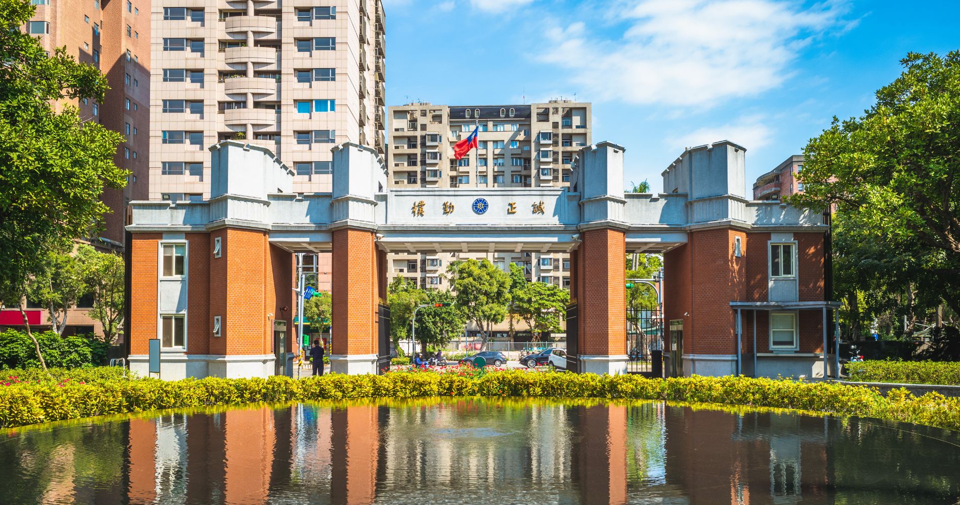National Taiwan Normal University – Historisches Backsteintor mit chinesischem Schriftzug und Wasserspiegelung davor.