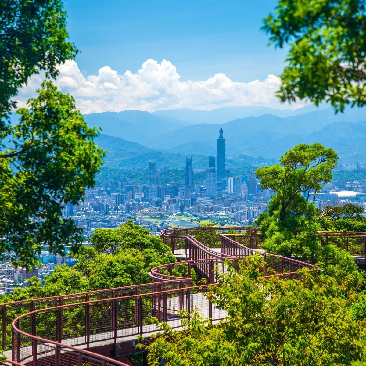 Taipei – Panoramablick vom Dajianshan auf die Skyline mit Taipei 101 und gewundenem Aussichtsweg im Grünen.