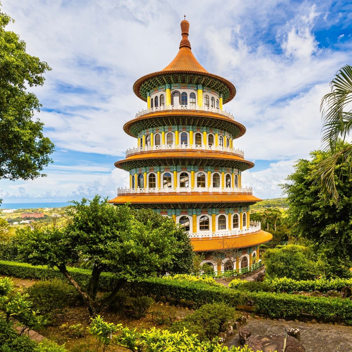 Taipei – Farbenfrohe mehrstöckige Pagode des Tianhou-Tempels in Danshui inmitten tropischer Vegetation.