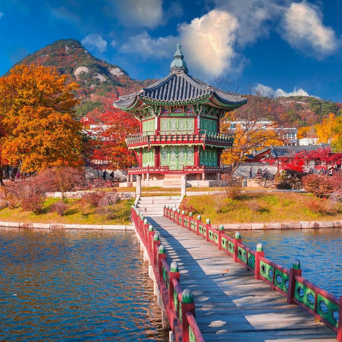 Seoul – Hyangwonjeong-Pavillon im Gyeongbokgung-Palast mit roter Holzbrücke und leuchtend herbstlichem Laub.