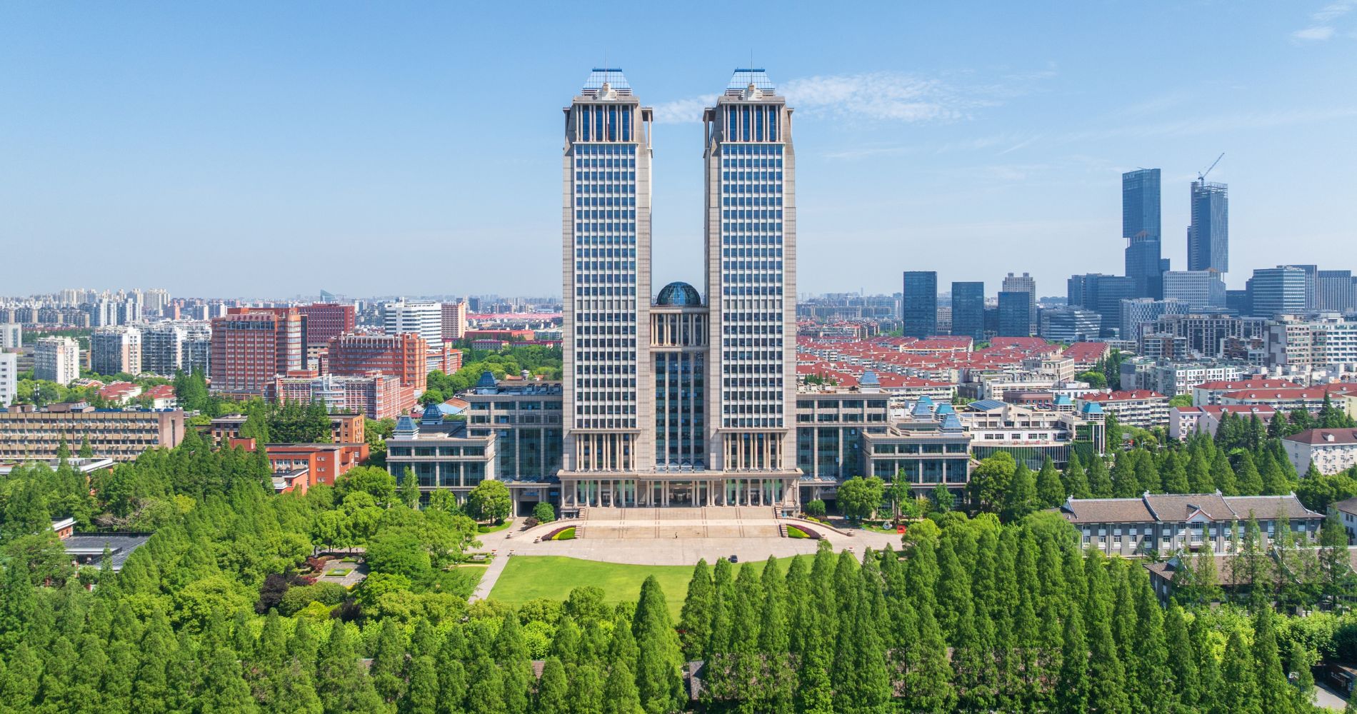 Fudan University Shanghai – Zwei markante Türme des Hauptgebäudes inmitten grüner Bäume und Stadtpanorama.