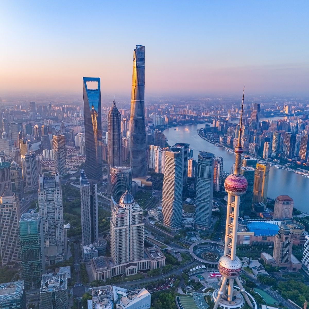 Shanghai Skyline bei Sonnenuntergang – Shanghai Tower, Oriental Pearl Tower und Huangpu-Fluss aus der Vogelperspektive.