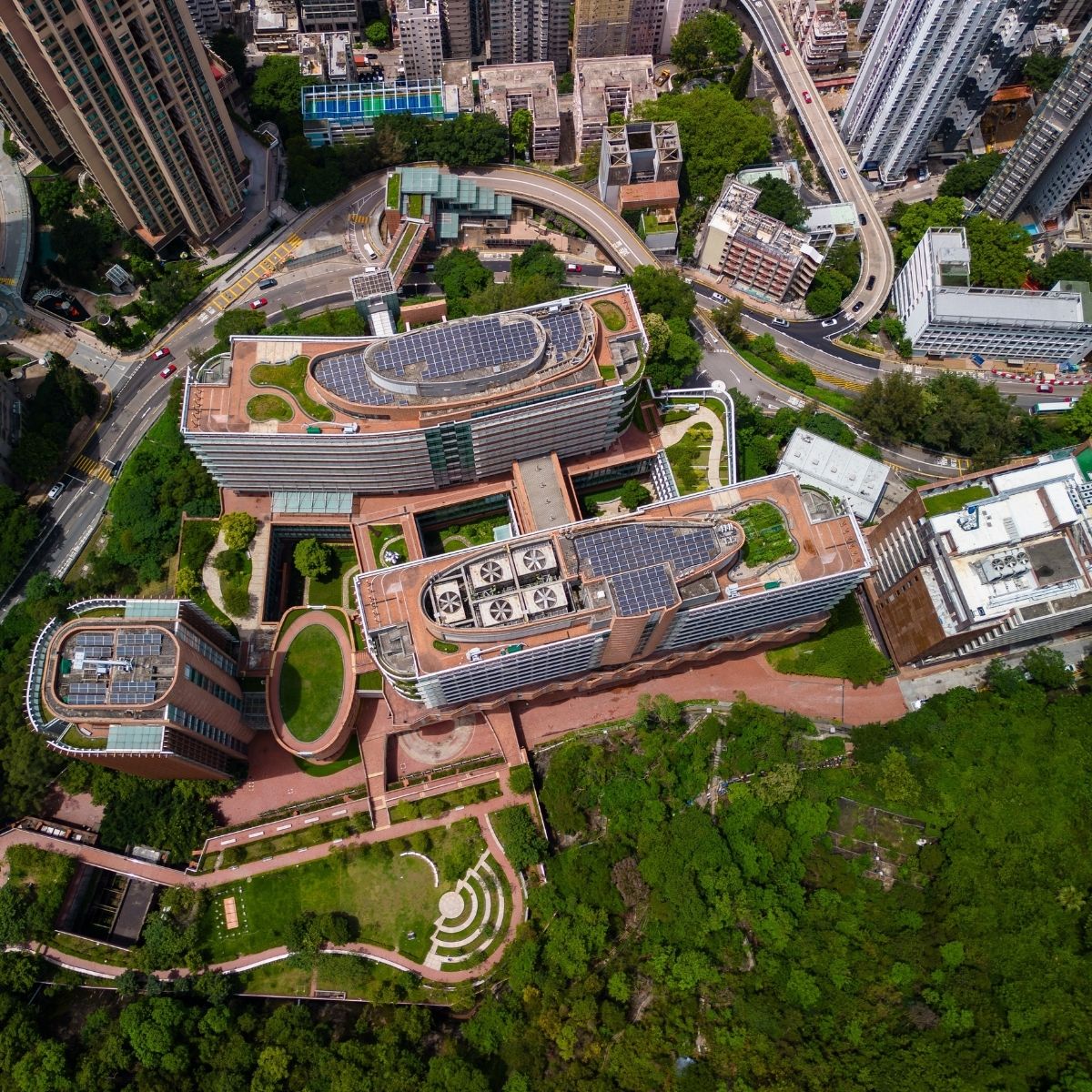 University of Hong Kong – Luftaufnahme des Campus mit Solardächern, Grünflächen und geschwungenen Gebäuden im Stadtgefüge.
