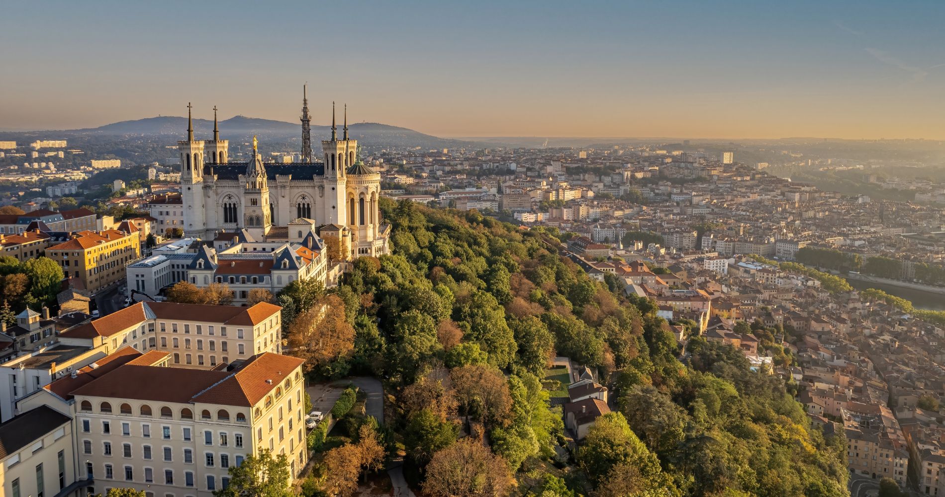 Lyon – Luftaufnahme der Basilique Notre-Dame de Fourvière auf dem Fourvière-Hügel mit Stadtpanorama im Abendlicht.