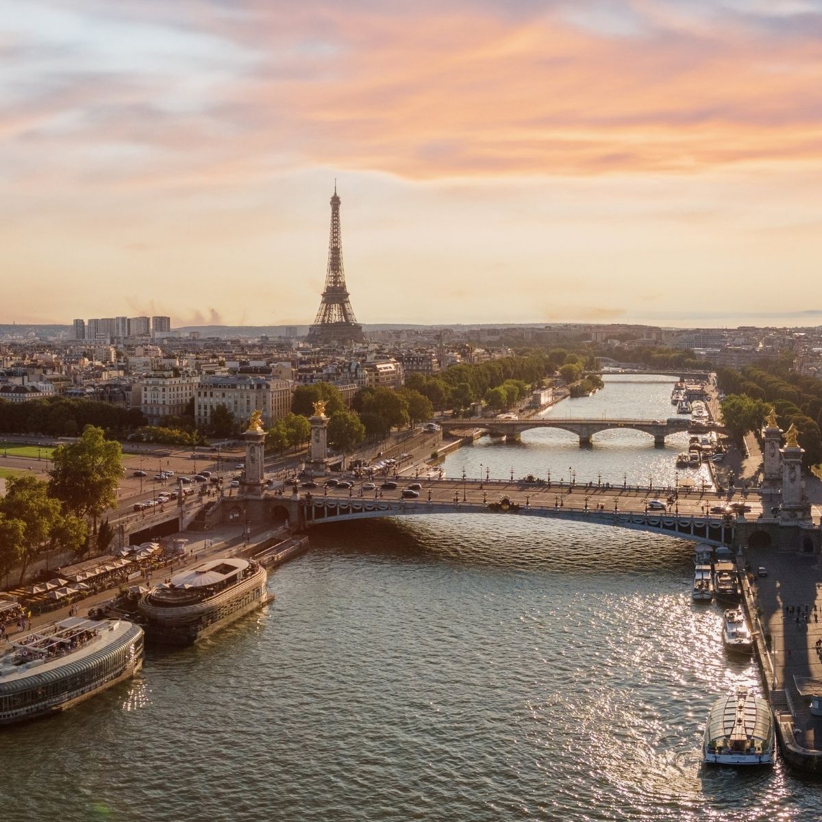 Paris – Luftaufnahme der Seine mit Pont Alexandre III, Eiffelturm und Ausflugsbooten im Abendlicht.