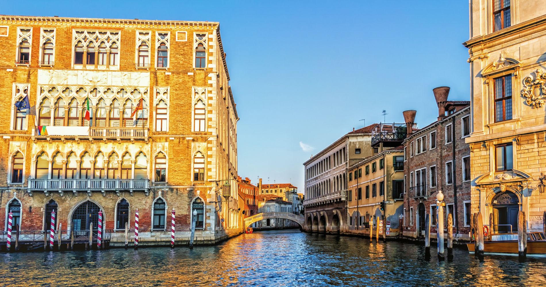 Università Ca' Foscari Venezia – Gotischer Palazzo am Kanal mit EU- und Italienflagge im Abendlicht.