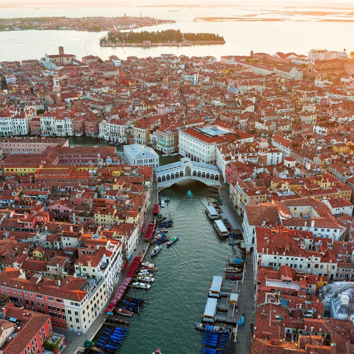 Venedig – Luftaufnahme der Altstadt mit Rialtobrücke, Canal Grande und roten Ziegeldächern bei Sonnenuntergang.