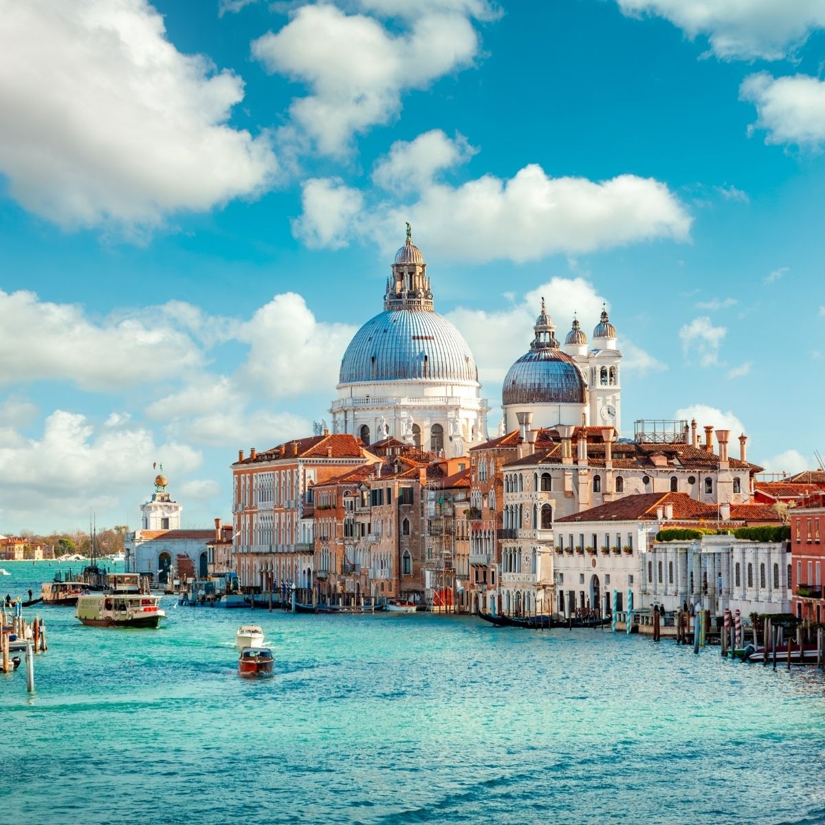 Venedig – Basilica di Santa Maria della Salute mit silberner Kuppel am Canal Grande mit Booten davor.