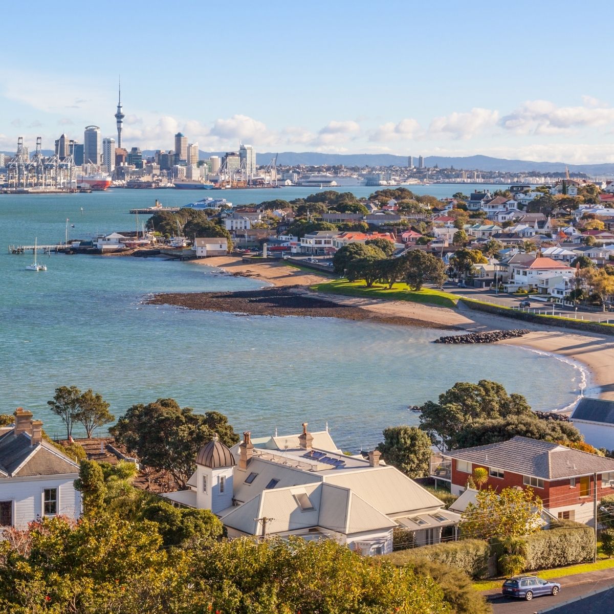Auckland – Blick über die Bucht von Devonport auf die Skyline mit Sky Tower und türkisfarbenem Hafenwasser.