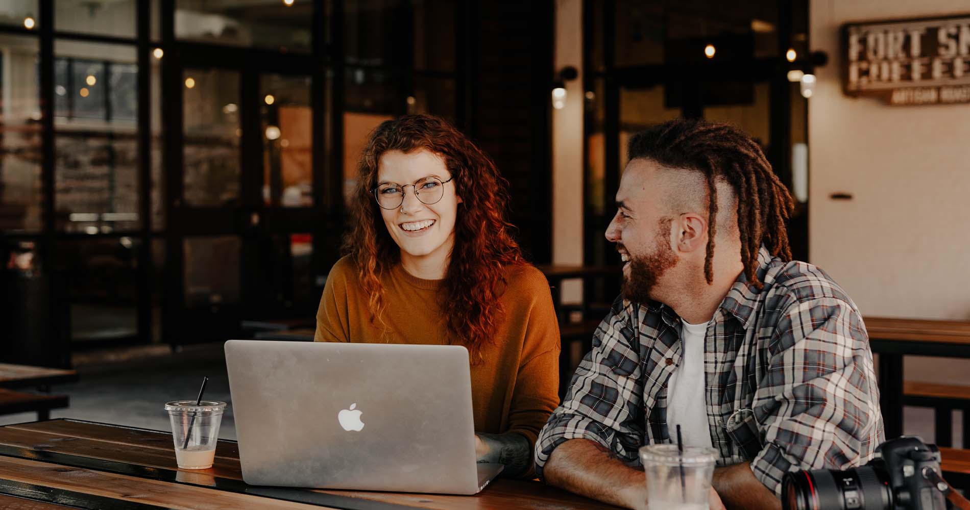 Personen sitzen vor einem Laptop und lachen miteinander