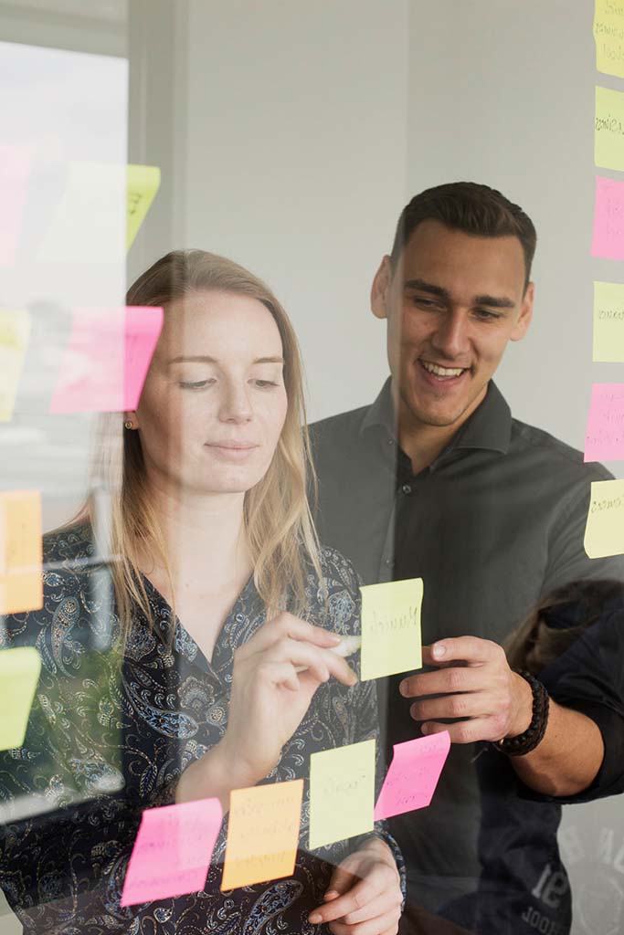 Studierende diskutieren über die Post-its auf einem Fenster