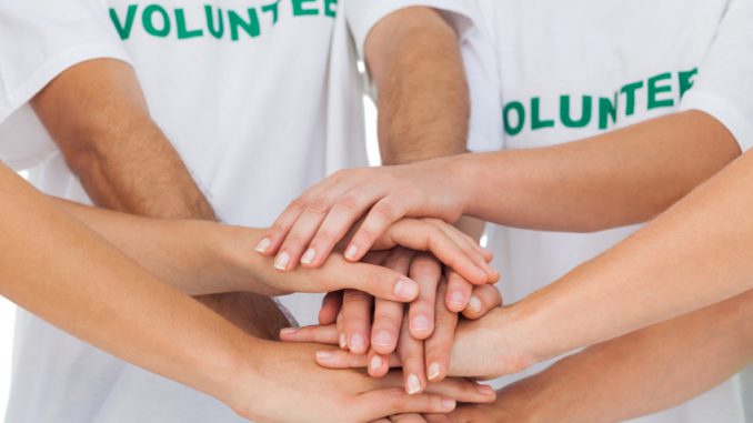 Group of volunteers piling up their hands together