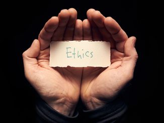 Zwei Hände, die einen handbeschriebenen Karton mit dem Wort "Ethics" halten