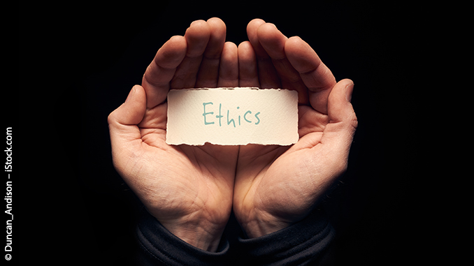 Zwei Hände, die einen handbeschriebenen Karton mit dem Wort "Ethics" halten