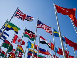 Flags of different nations against a blue sky