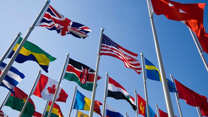 Flags of different nations against a blue sky