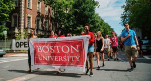Students walking through the street with a large Boston University banner