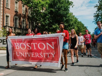 Students walking through the street with a large Boston University banner