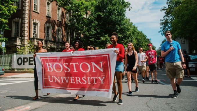Students walking through the street with a large Boston University banner