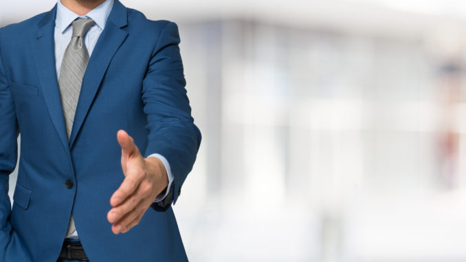 Man in suit with his hand extended forward for a handshake