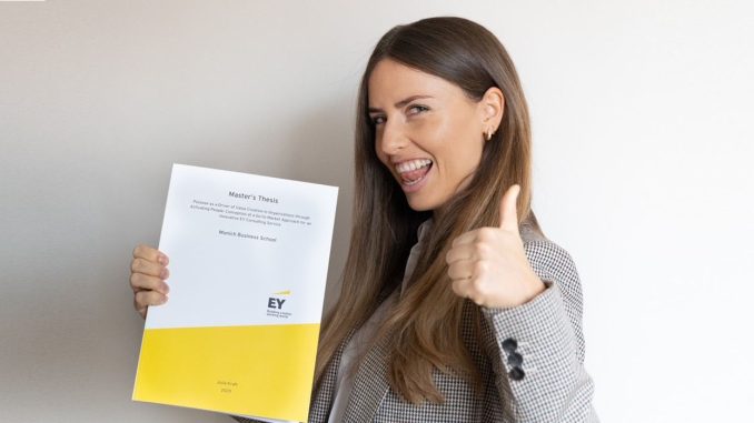 Julia Kraft, alumna of Munich Business School, with her master's thesis in hand and doing a thumbs up