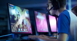 Young man with headset looking intently at a screen where he is running an e-sports game