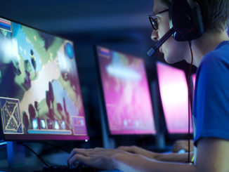 Young man with headset looking intently at a screen where he is running an e-sports game