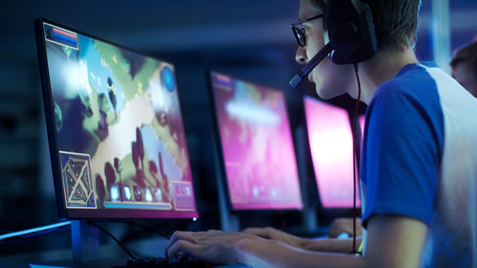 Young man with headset looking intently at a screen where he is running an e-sports game