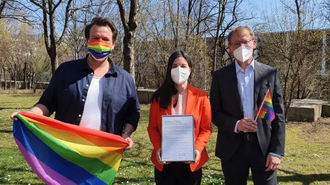 Munich Business School: Charta der Vielfalt / German Diversity Charter Christoph Schlottmann, Dr. Christine Menges and Prof. Dr. Stefan Baldi with the signed Diversity Charter and Pride flags in the garden of Munich Business School.