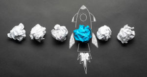 Crumpled paper balls and a rocket drawing on a blackboard as a symbol for founding a start-up.
