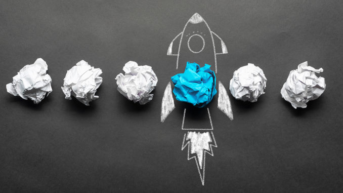 Crumpled paper balls and a rocket drawing on a blackboard.