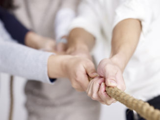 group of business people playing tug-of-war, focus on hands