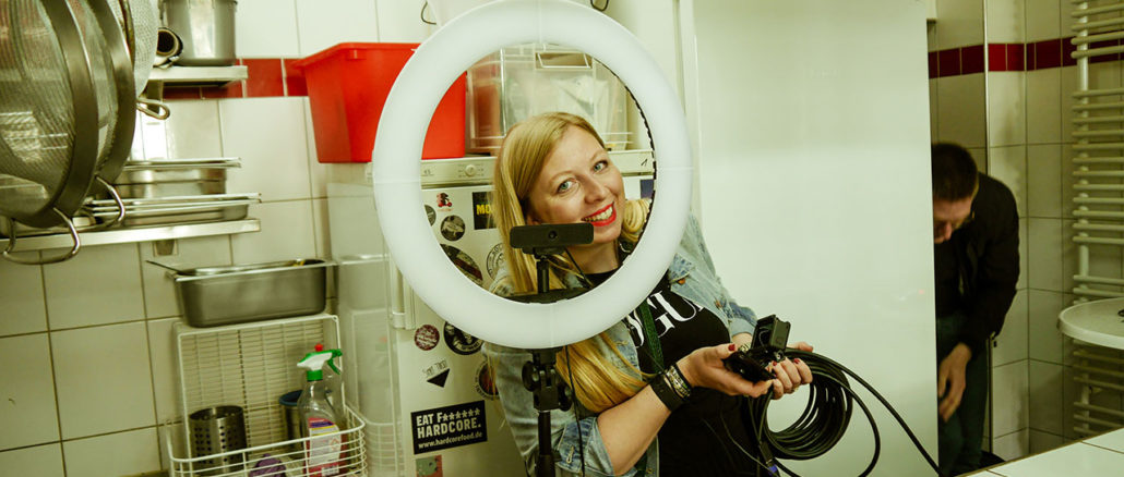 Marisa looks smiling through a ring light into the camera