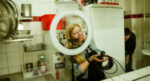 Marisa Bogumil, student at Munich Business School and founder of the start-up Cook-it like, looks smiling through a ring light into the camera