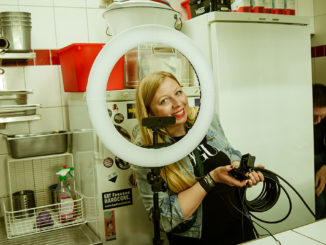 Marisa Bogumil, student at Munich Business School and founder of the start-up Cook-it like, looks smiling through a ring light into the camera