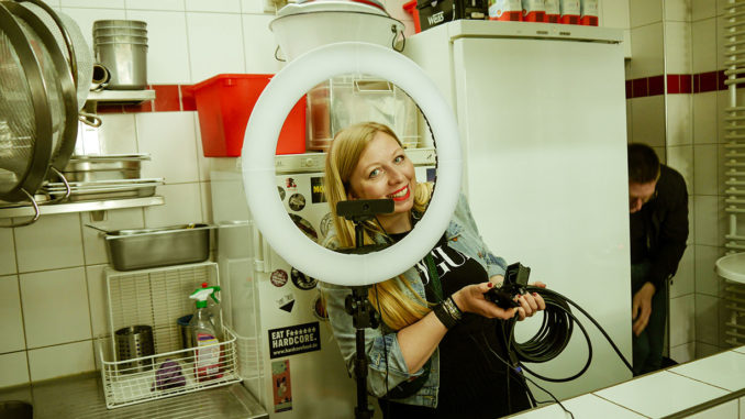 Marisa Bogumil, student at Munich Business School and founder of the start-up Cook-it like, looks smiling through a ring light into the camera