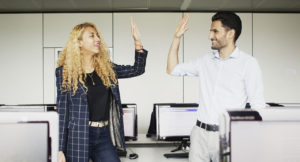 Two students high-fiving in the computer lab of Munich Business School.