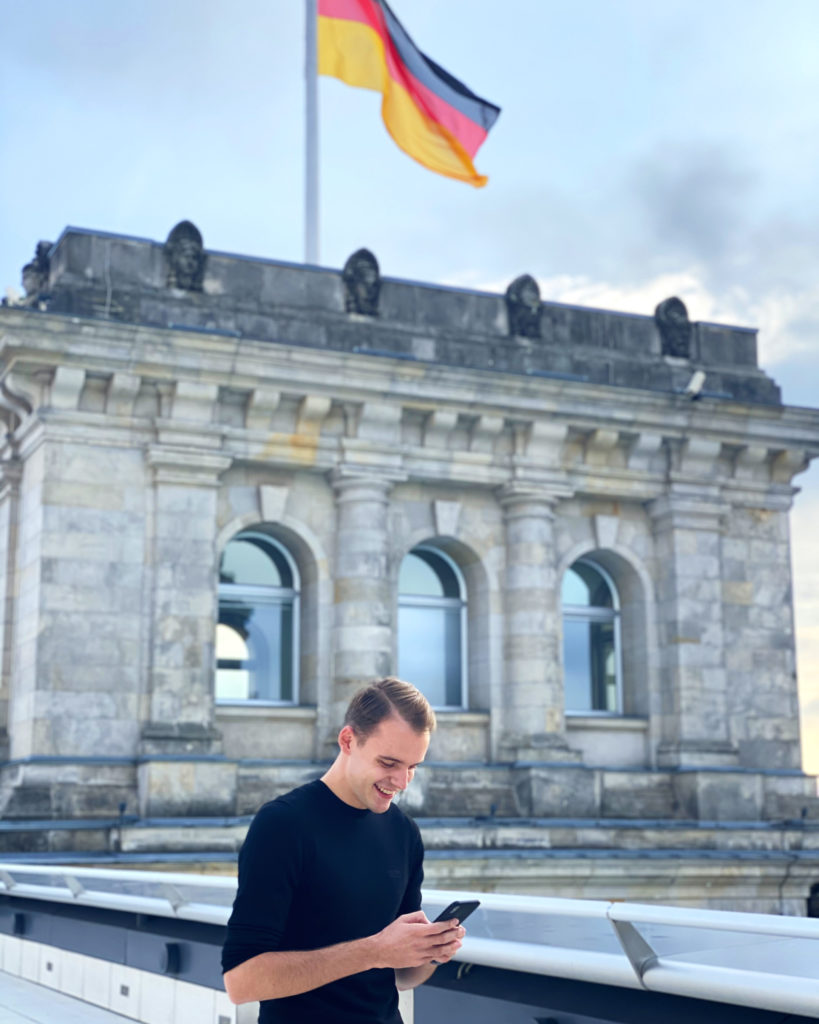 Felix Schmitt, student of Munich Business School, typing on his phone in front of the Bundestag in Berlin
