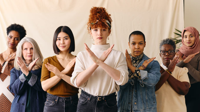 A group of women gesturing the "Break the Bias" pose for International Women's Day 2022