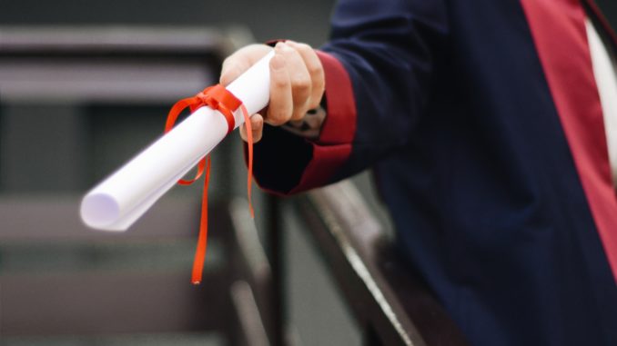 Munich Business School: Is DBA or PhD better? Close-up of a hand handing over a diploma as a roll of paper.