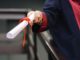 Close-up of a hand handing over a diploma as a roll of paper.