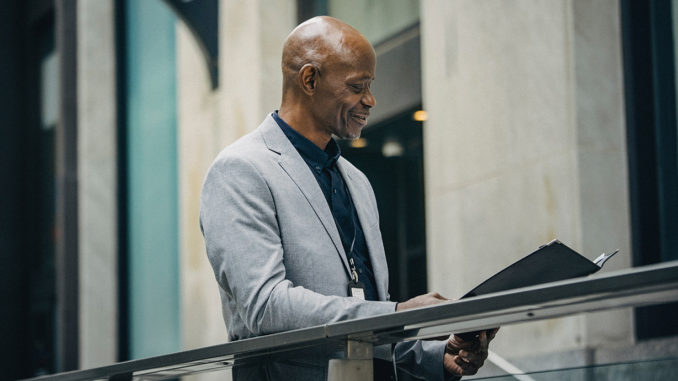 African American manager reading documents in folder.