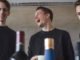 The three founders of spiritory laughing - Janis Wilczura, alumnus of Munich Business School in the middle; bottle tops in foreground