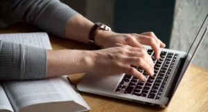 Close up of man typing his thesis on laptop