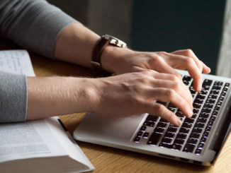 Close up of man typing his thesis on laptop