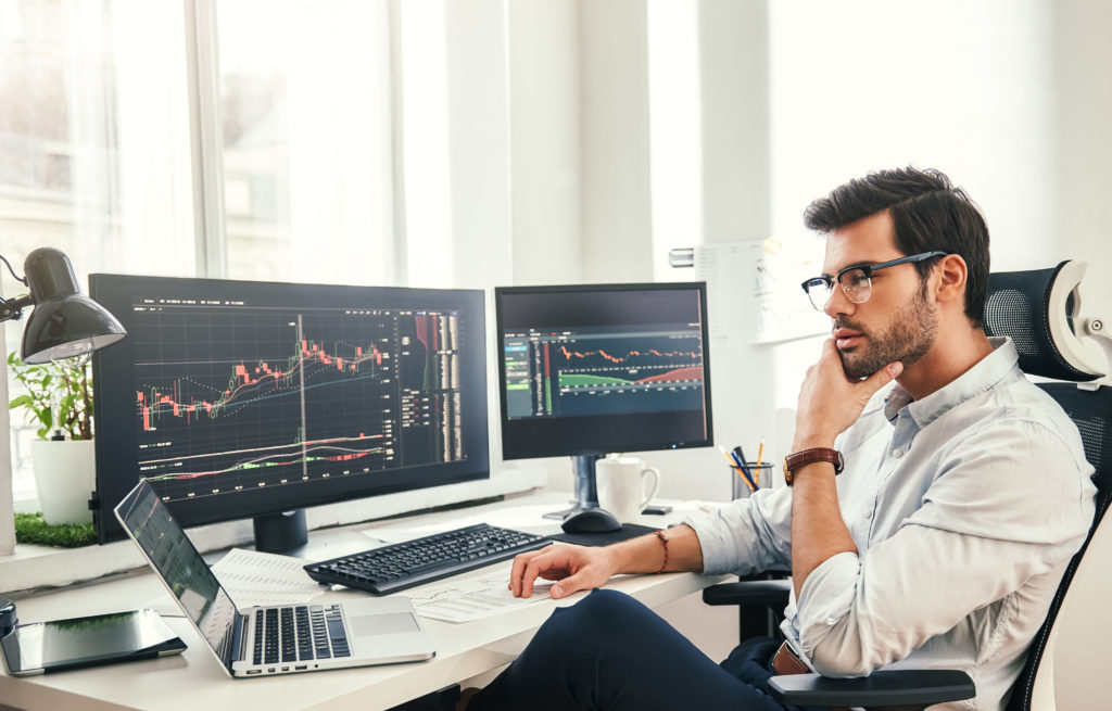 oung business graduate analyzing tables and graphs in front of several screens