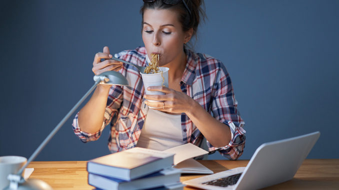 Food for the brain: Female student eating Asian noodles while learning at home